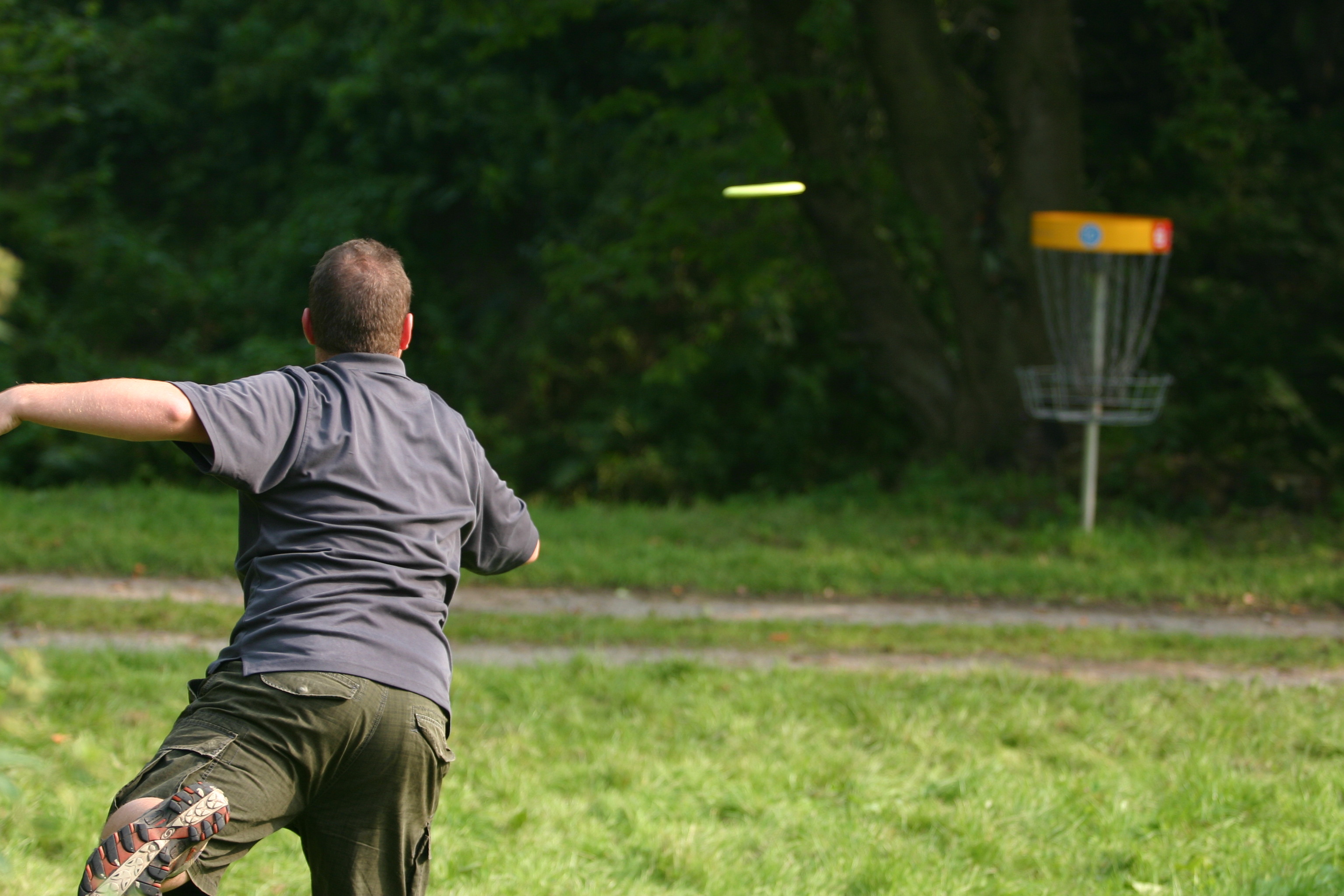 Ein Mann wirft eine Disc-Golf Scheibe Richtung Wurfkorb. Ein Mann wirft eine Disc-Golf Scheibe Richtung Wurfkorb.