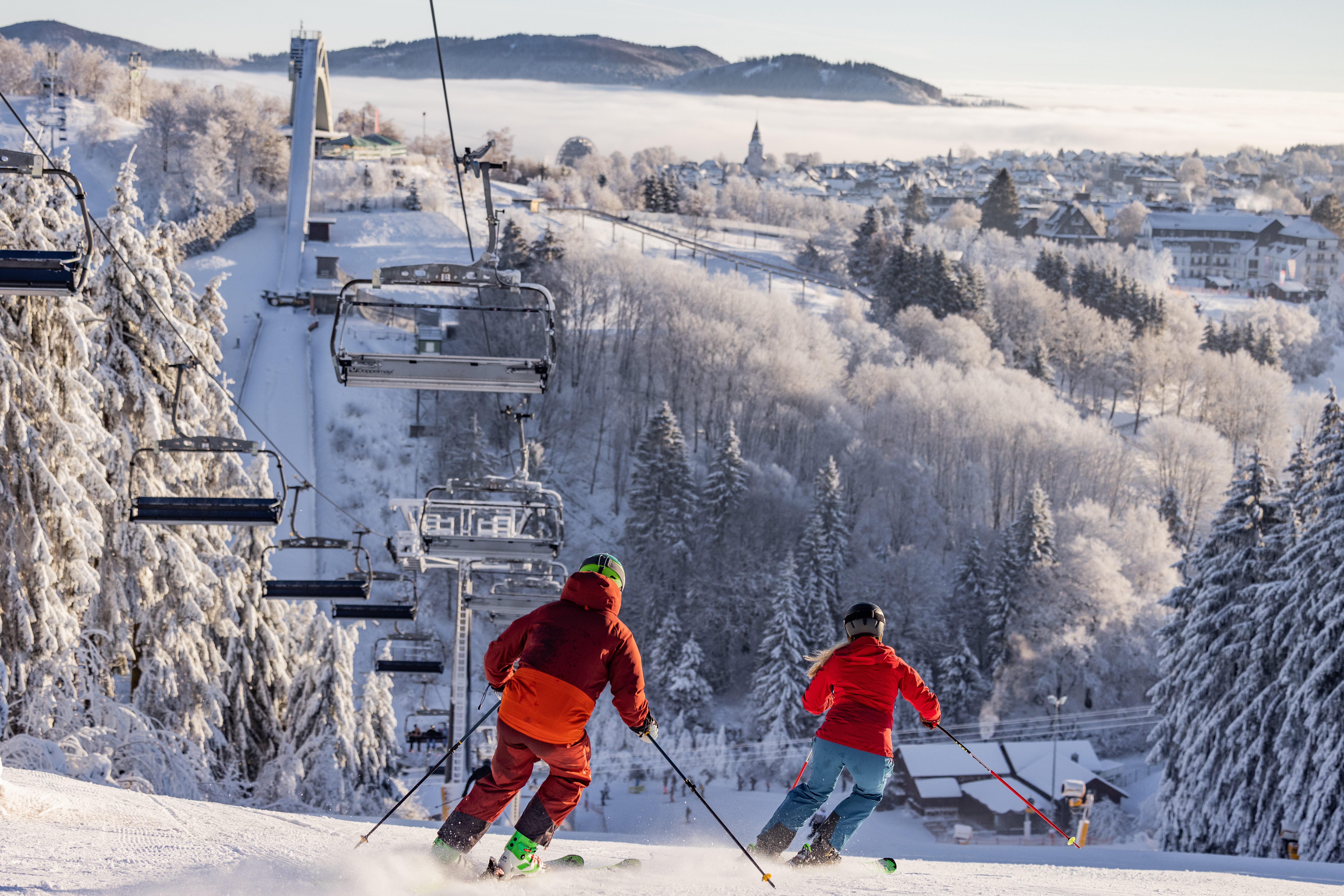 Ein Sessellift mit der St. Georg SDchanze im Hintergrund und Skifahrern auf der Piste. Ein Sessellift mit der St. Georg SDchanze im Hintergrund und Skifahrern auf der Piste.