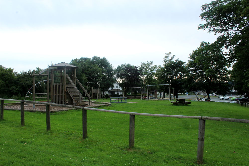 Spielplatz mit Kletterüst mit Rutsche und Schaukel.