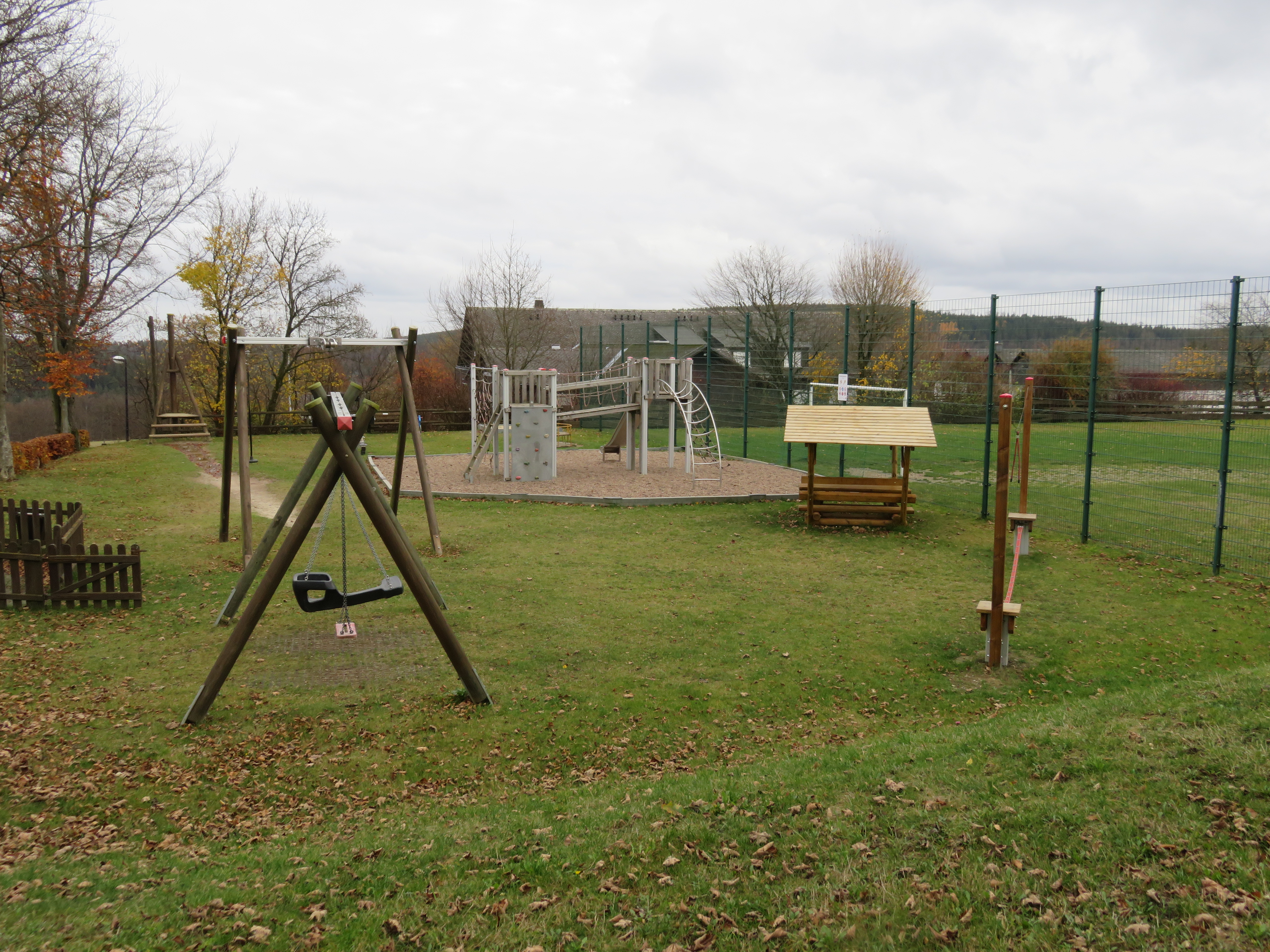 Spielplatz mit Klettergerüst, Schaukel und Wippe.