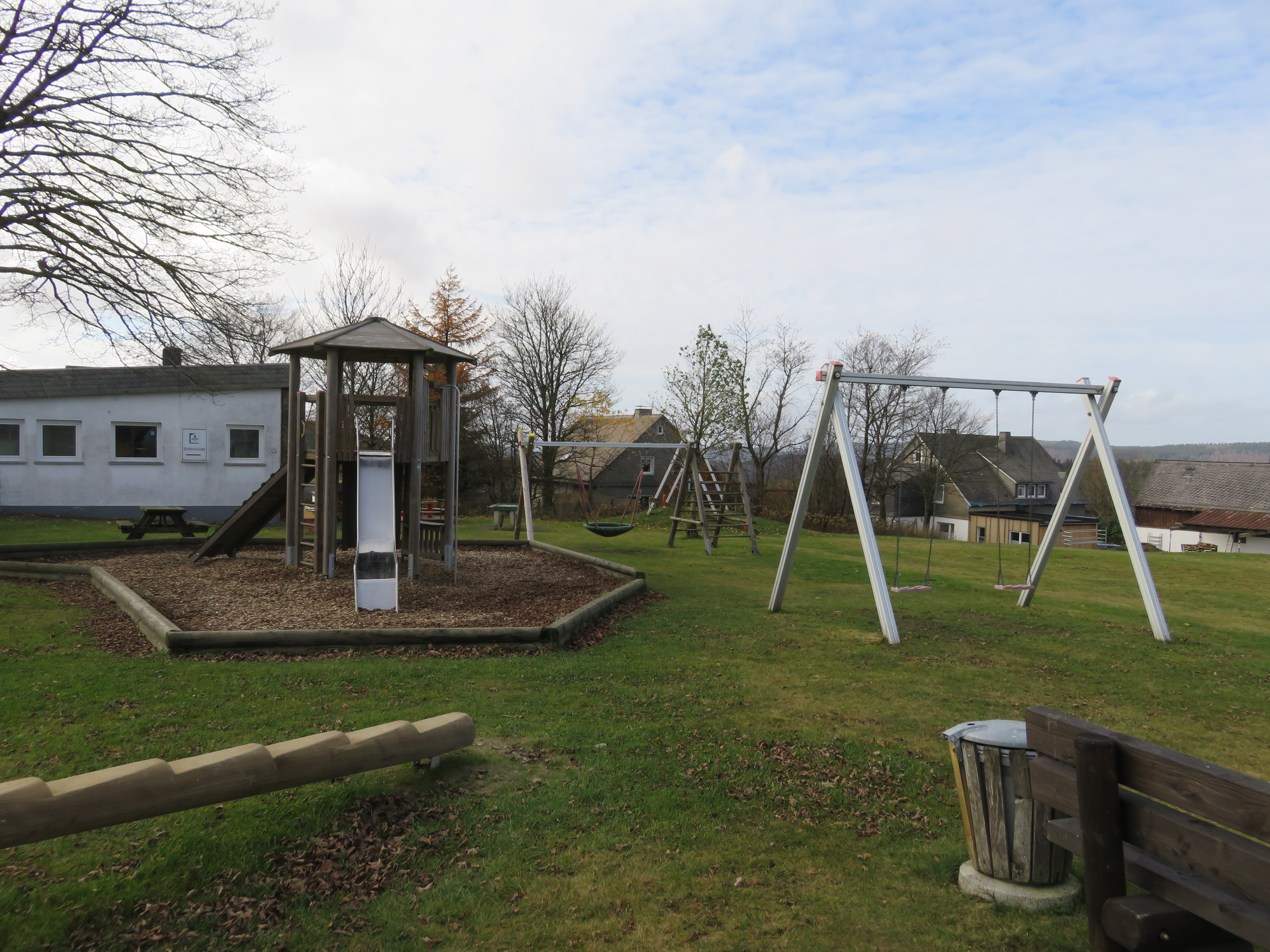 Spielplatz mit Klettergerüst, Rutsche, Sandkasten und Schaukel.