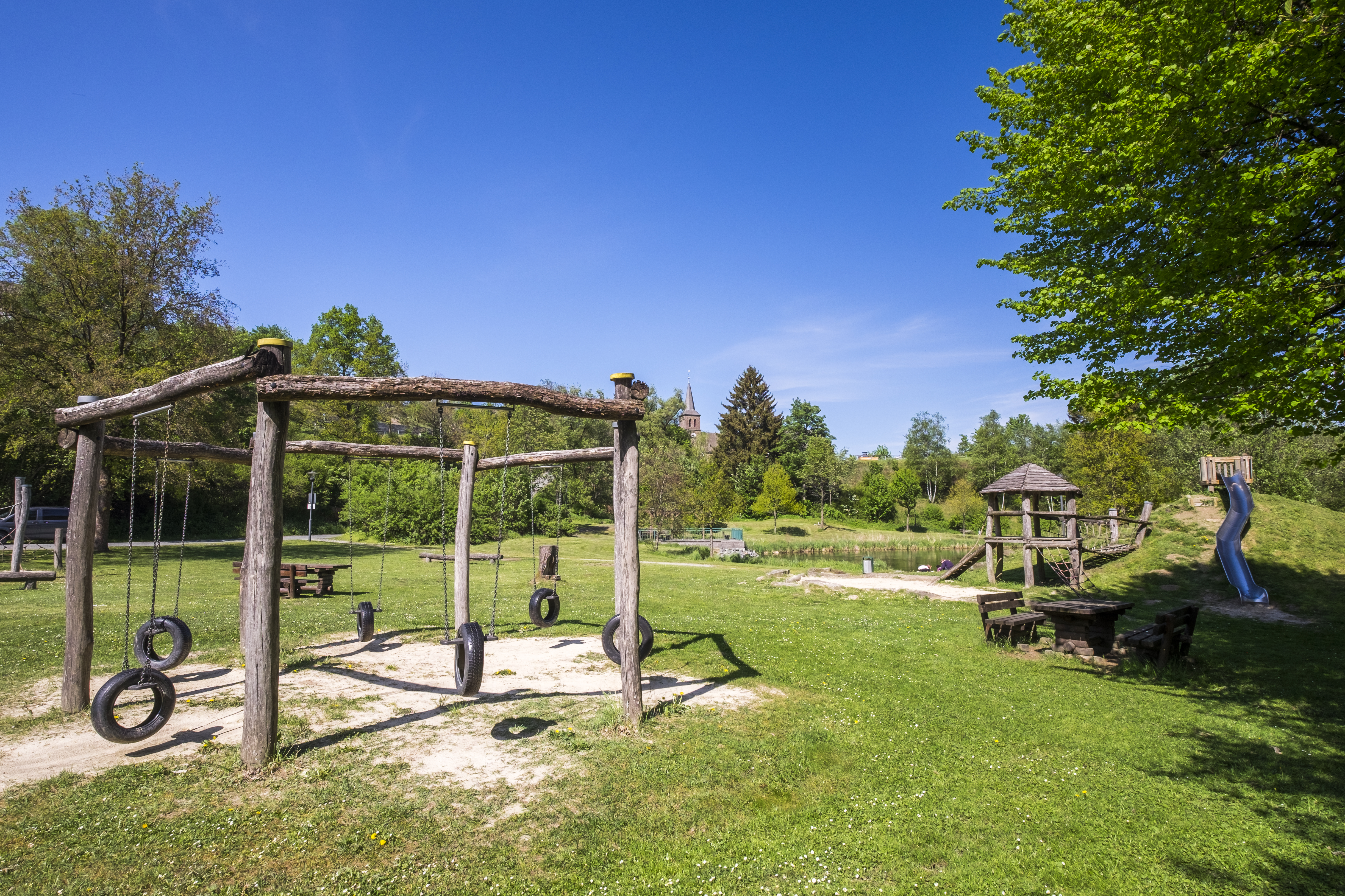 Ein Spielplatz mit Klettergerüst, Rutsche und Schaukeln.
