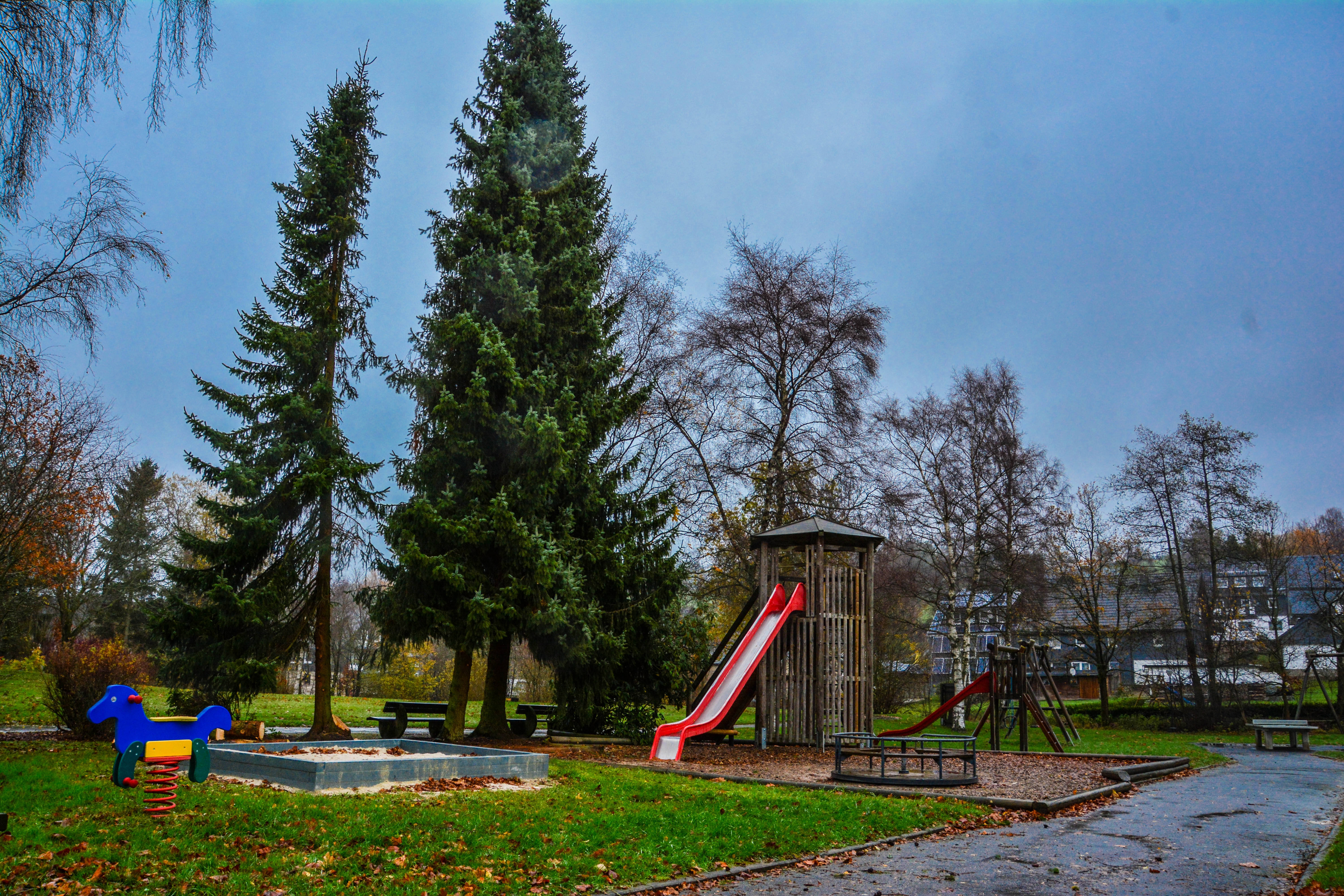 Spielplatz mit Klettergerüst, Rutsche, Wipptier und Sandkasten.
