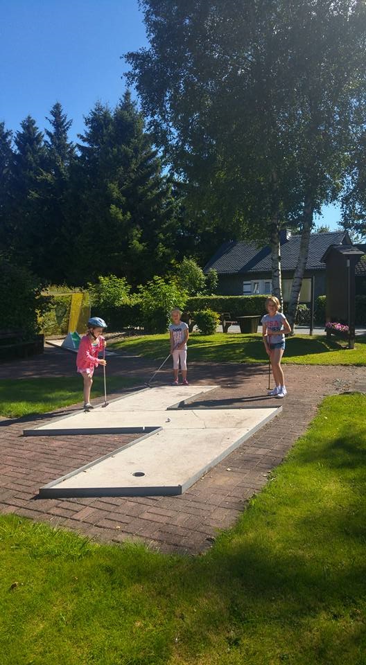 Drei Personen beim Minigolf spielen.