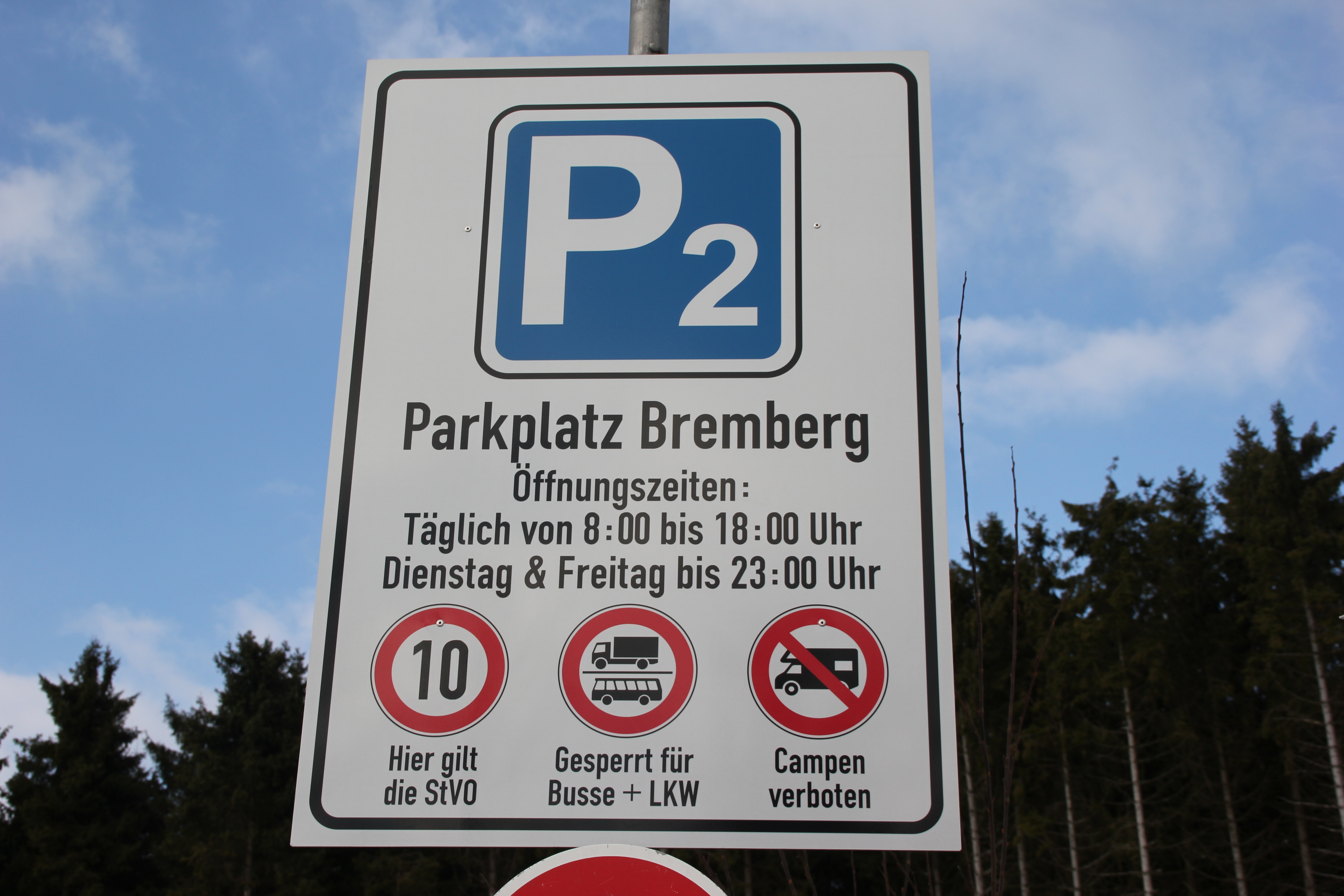 Parkplatzschild mit der Aufschrift P2 Parkplatz Bremberg und den Öffnungszeiten.