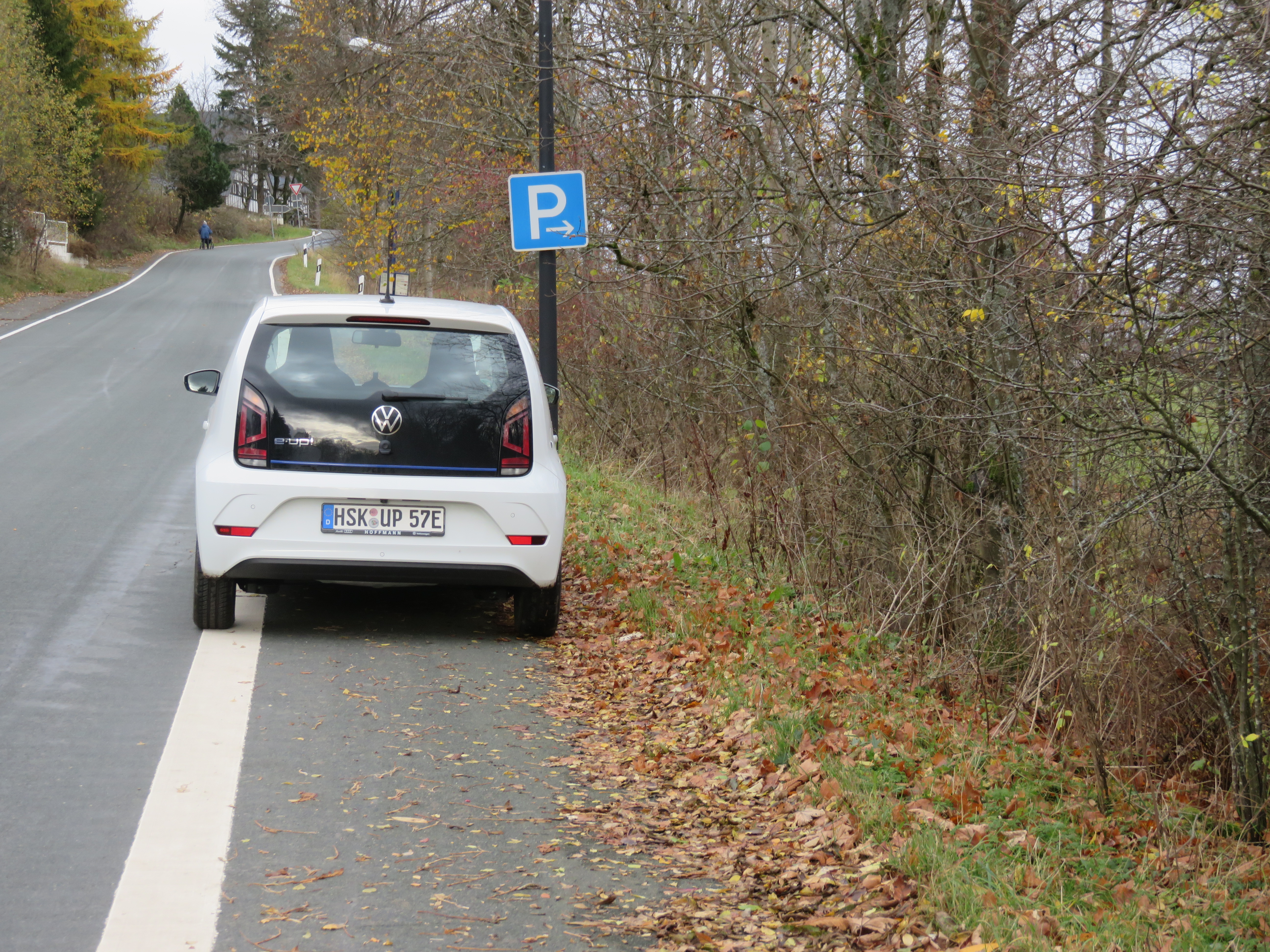 Parkstreifen neben einer Hauptverkehrsstraße mit einem weißen geparkten Auto.