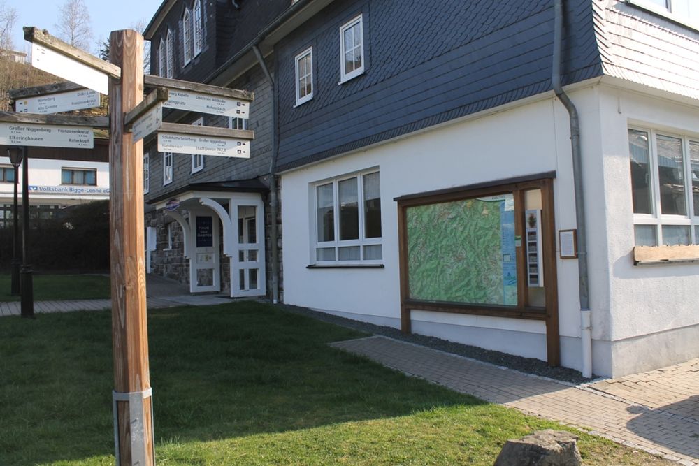 Informationstafel mit Wanderkarte vor einer Hauswand.