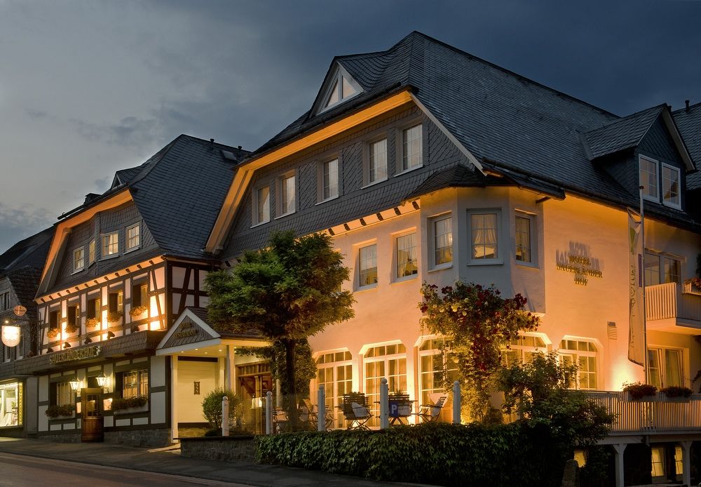 Außenansicht des beleuchteten Hotels Sauerländer Hof in der Abenddämmerung.