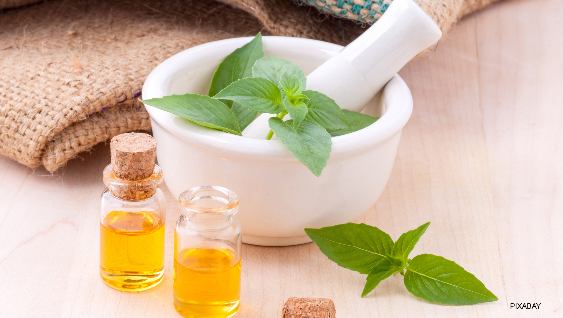 Ein Mörser mit verschiedenen Ölfläschchen und Kräutern auf einem Tisch.