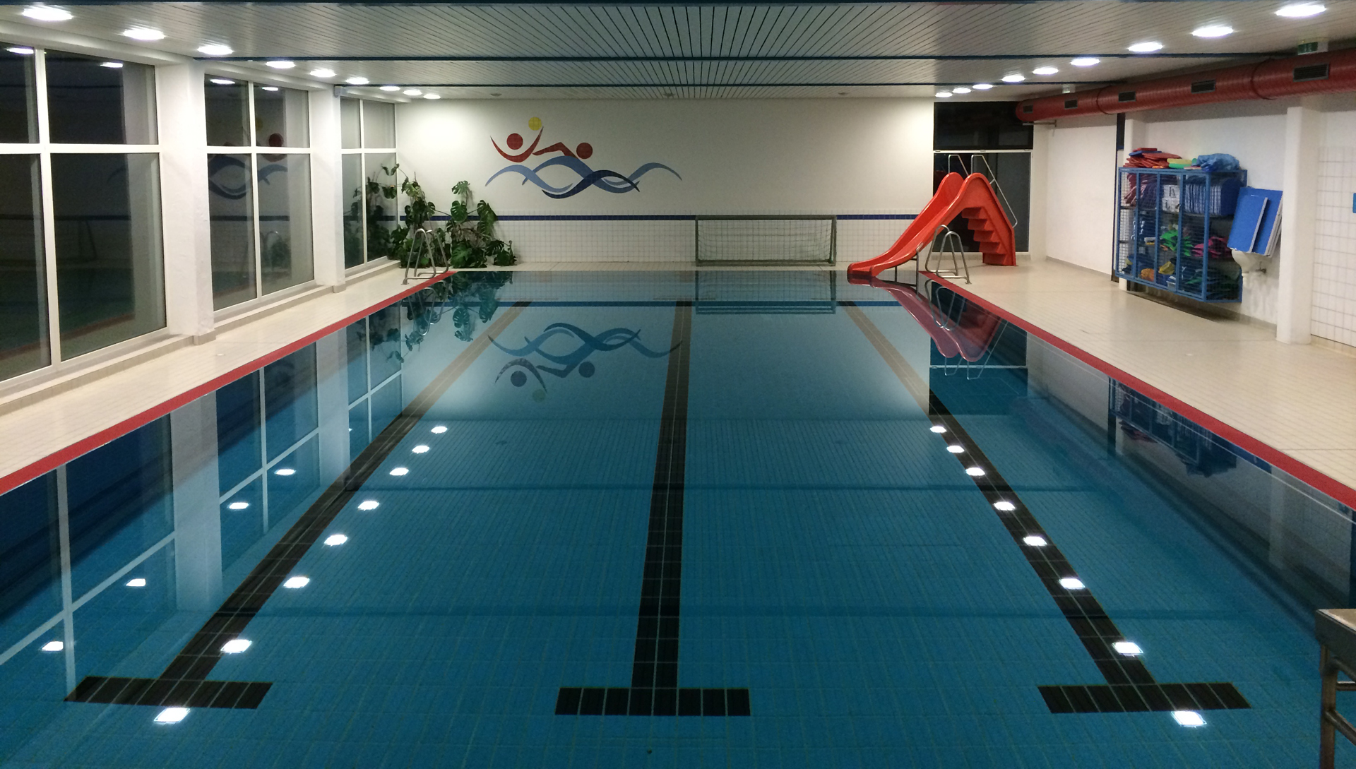 Hallenbad mit Kinderrutsche am Beckenrand.