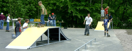 Eine Inline-Skating Bahn mit einigen Hindernissen und Personen mit Skateboards.