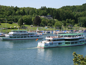 Zwei Personenschiffe auf einem See vor Wald und Wiesen. Zwei Personenschiffe auf einem See vor Wald und Wiesen.