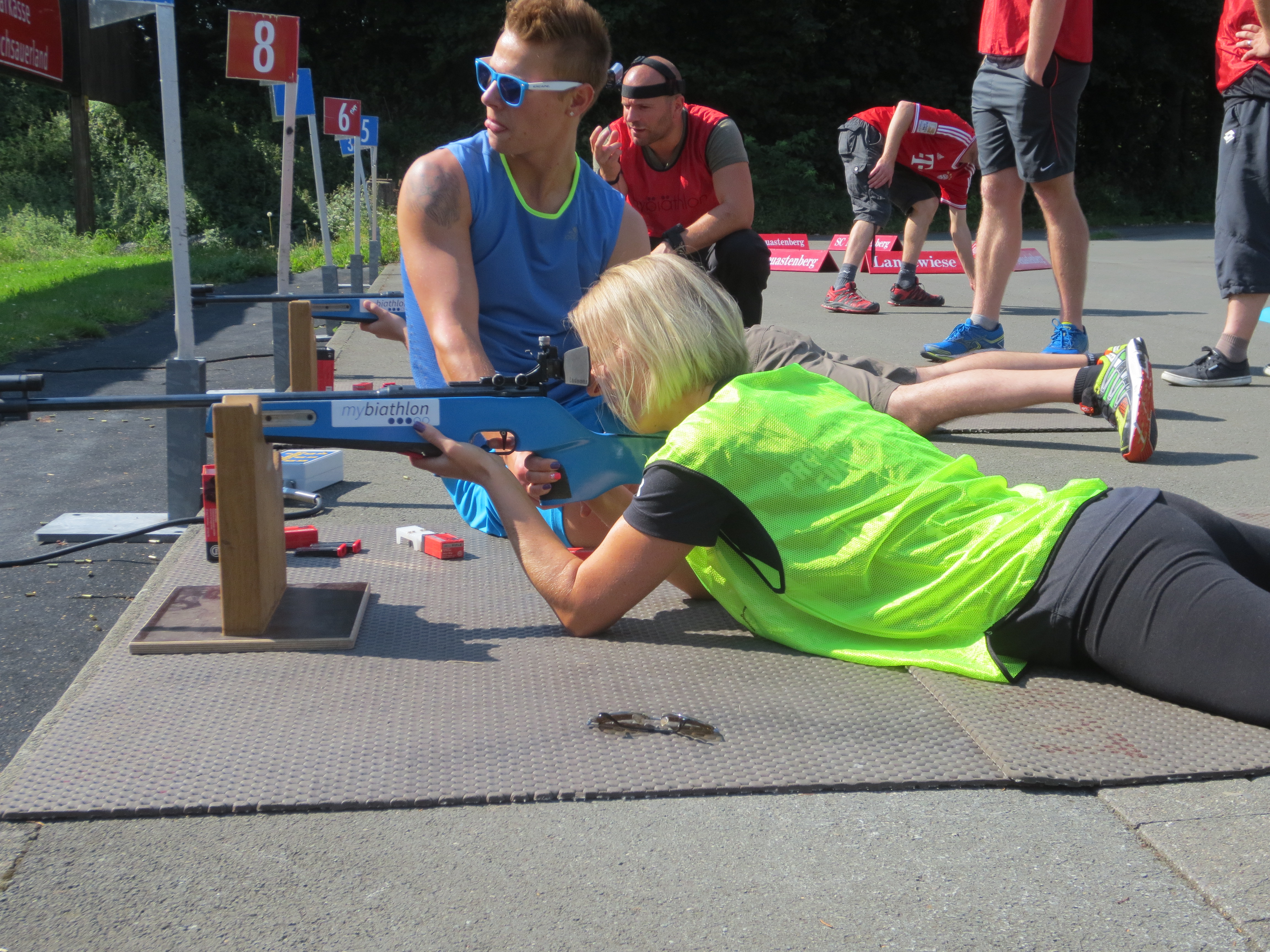 Eine Frau zielt auf dem Boden liegend mit einem Gewehr Auf eine Zielscheibe.