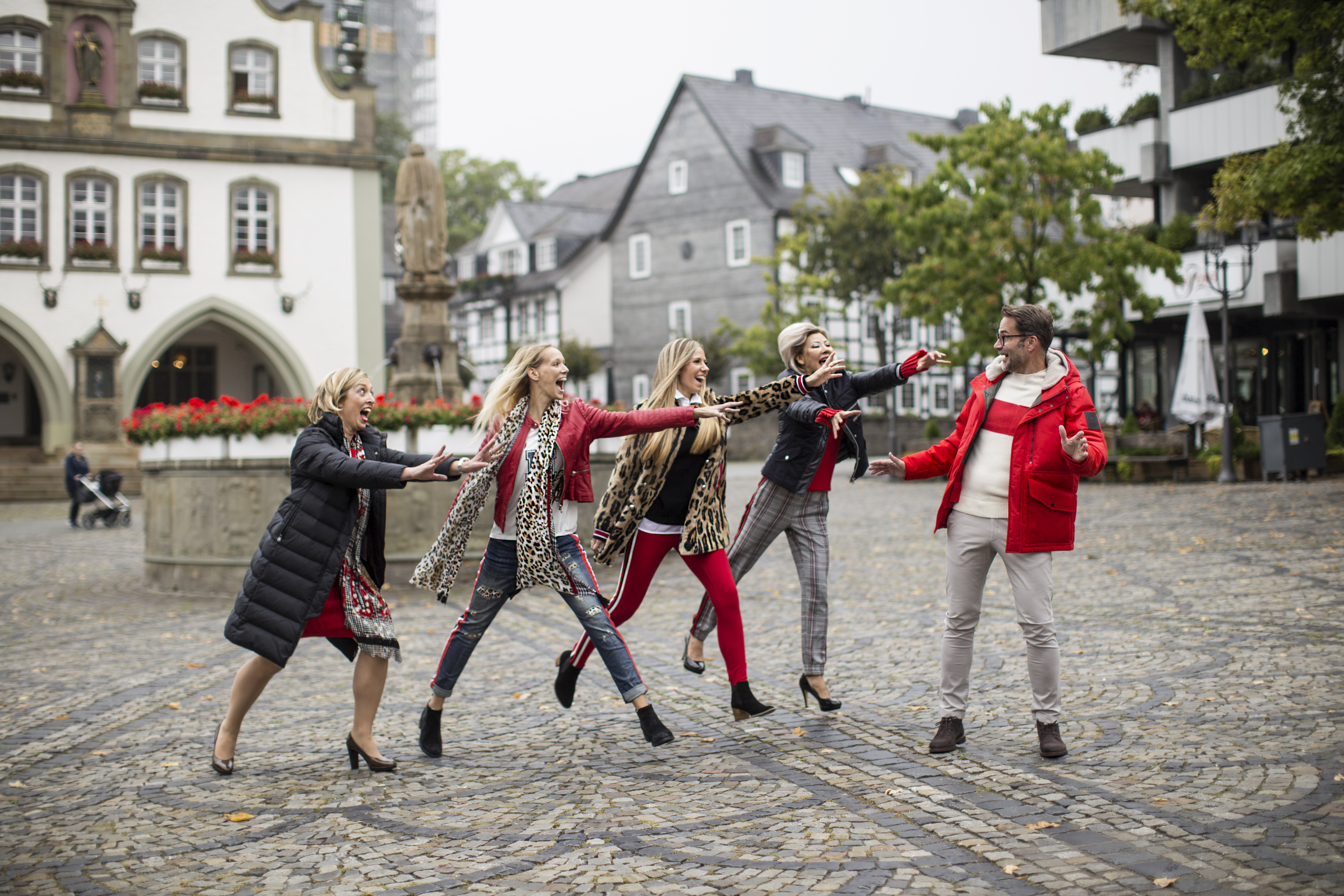Mehrere Personen auf einem Marktplatz in moderner Kleidung.