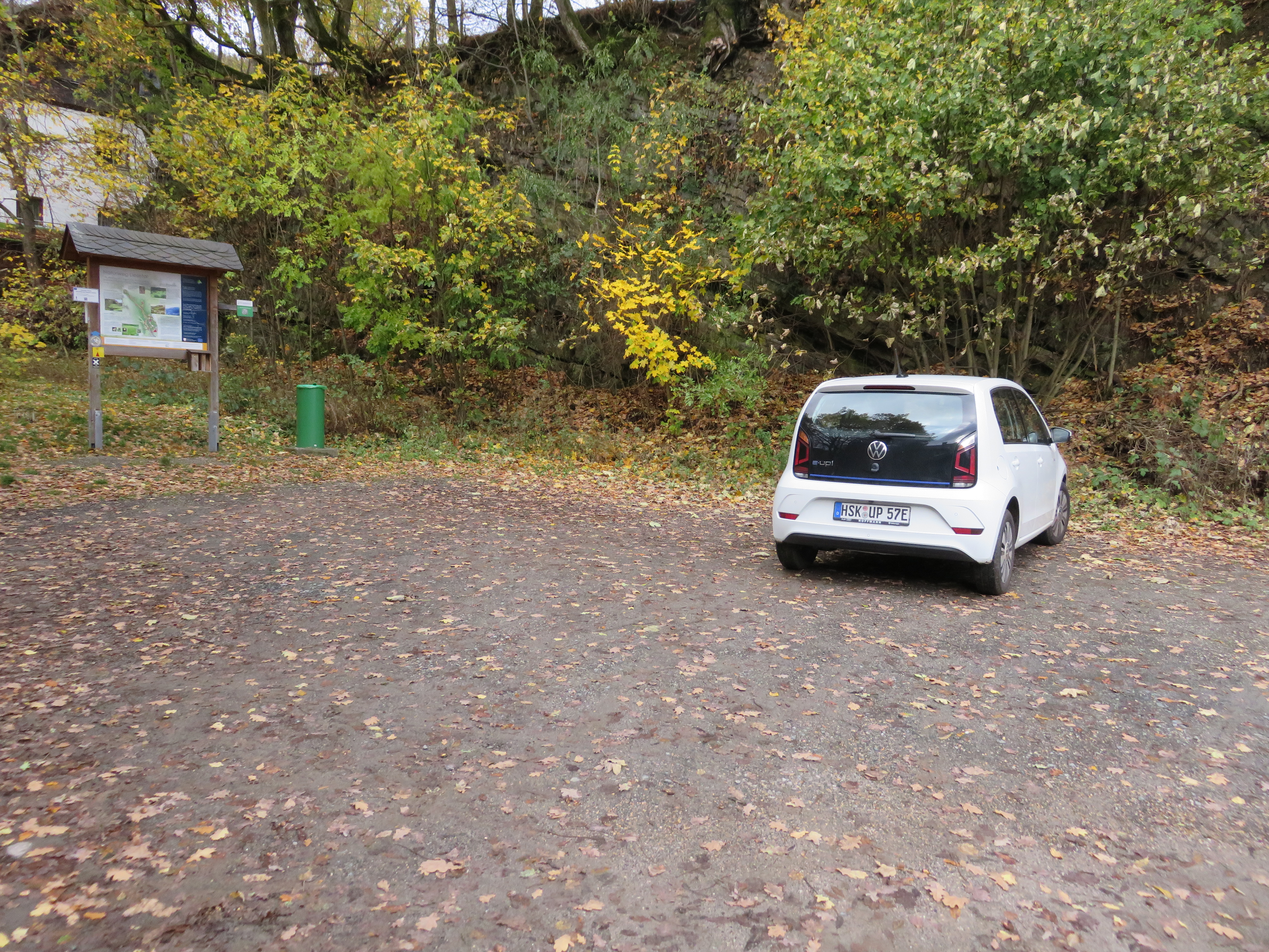 Ein Waldparkplatz mit einem weißen geparkten Auto.