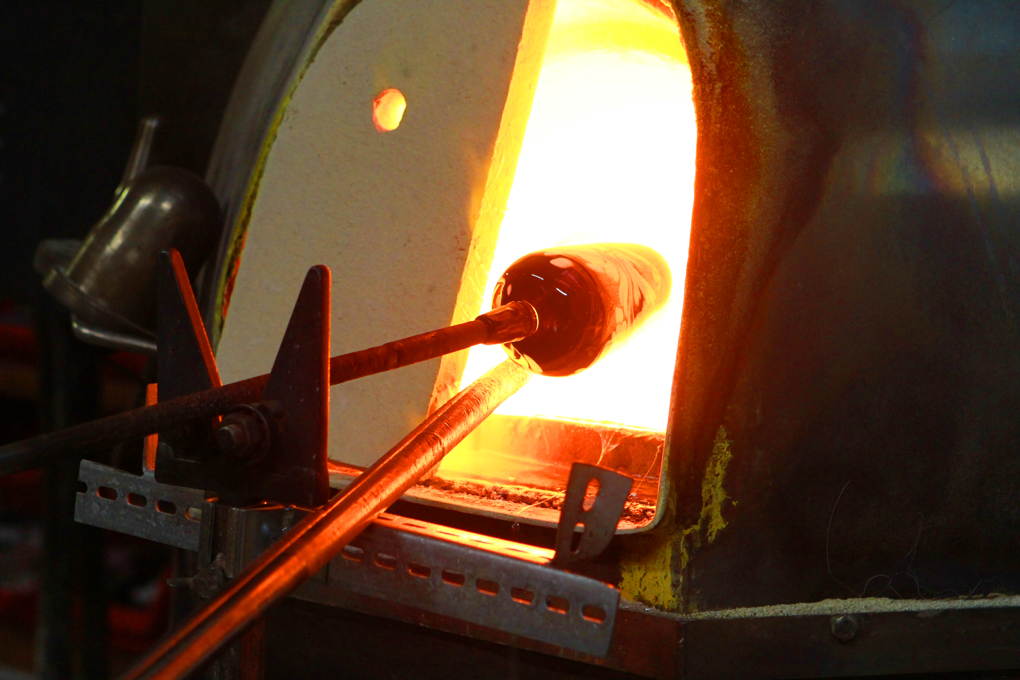 Gläsernes Material wird an einem speziellen Stock ins Feuer gehalten.