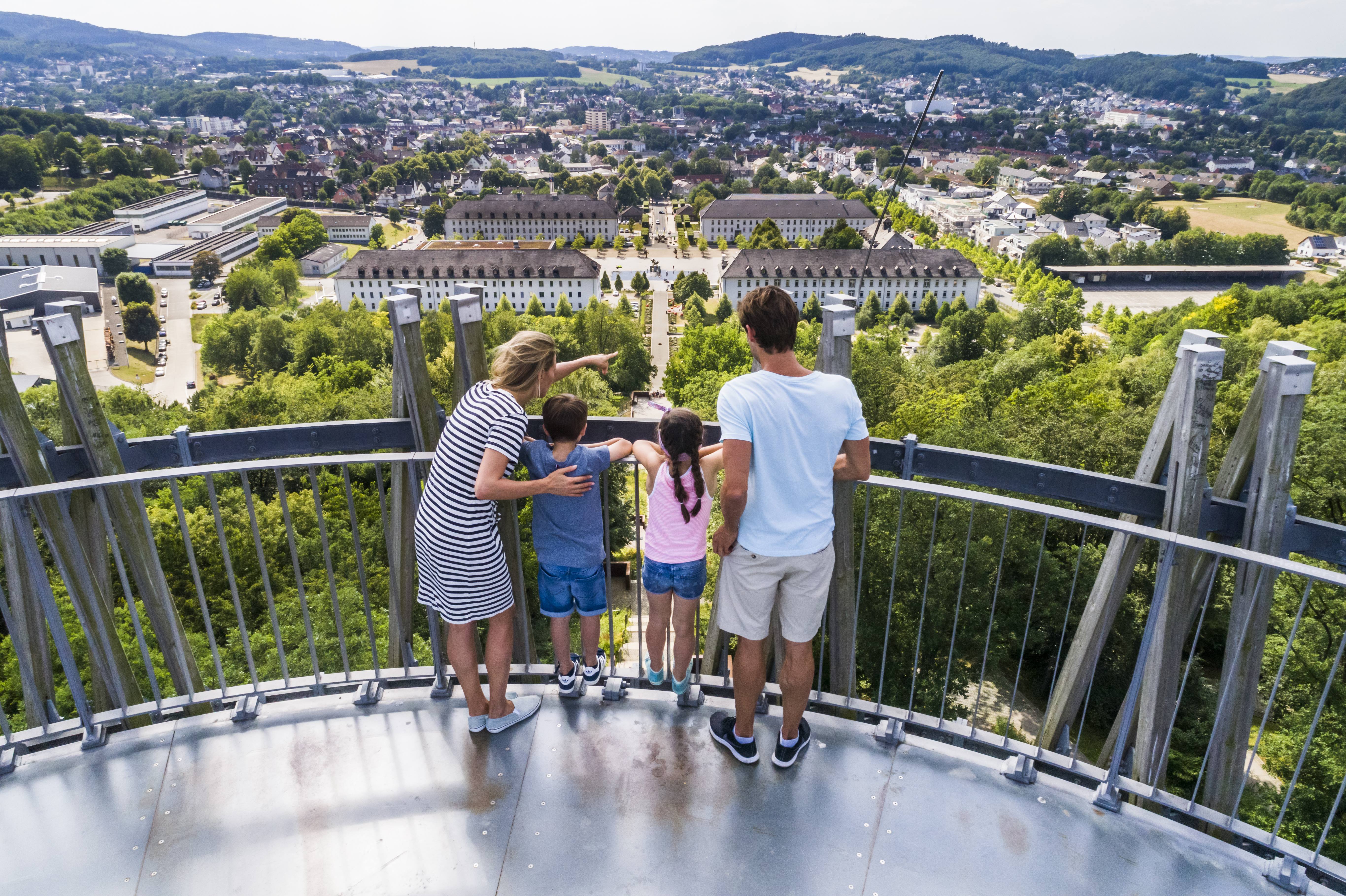 Eine Familie mit zwei Kindern steht auf einer Aussichtsplattform und genießt die weite Aussicht.