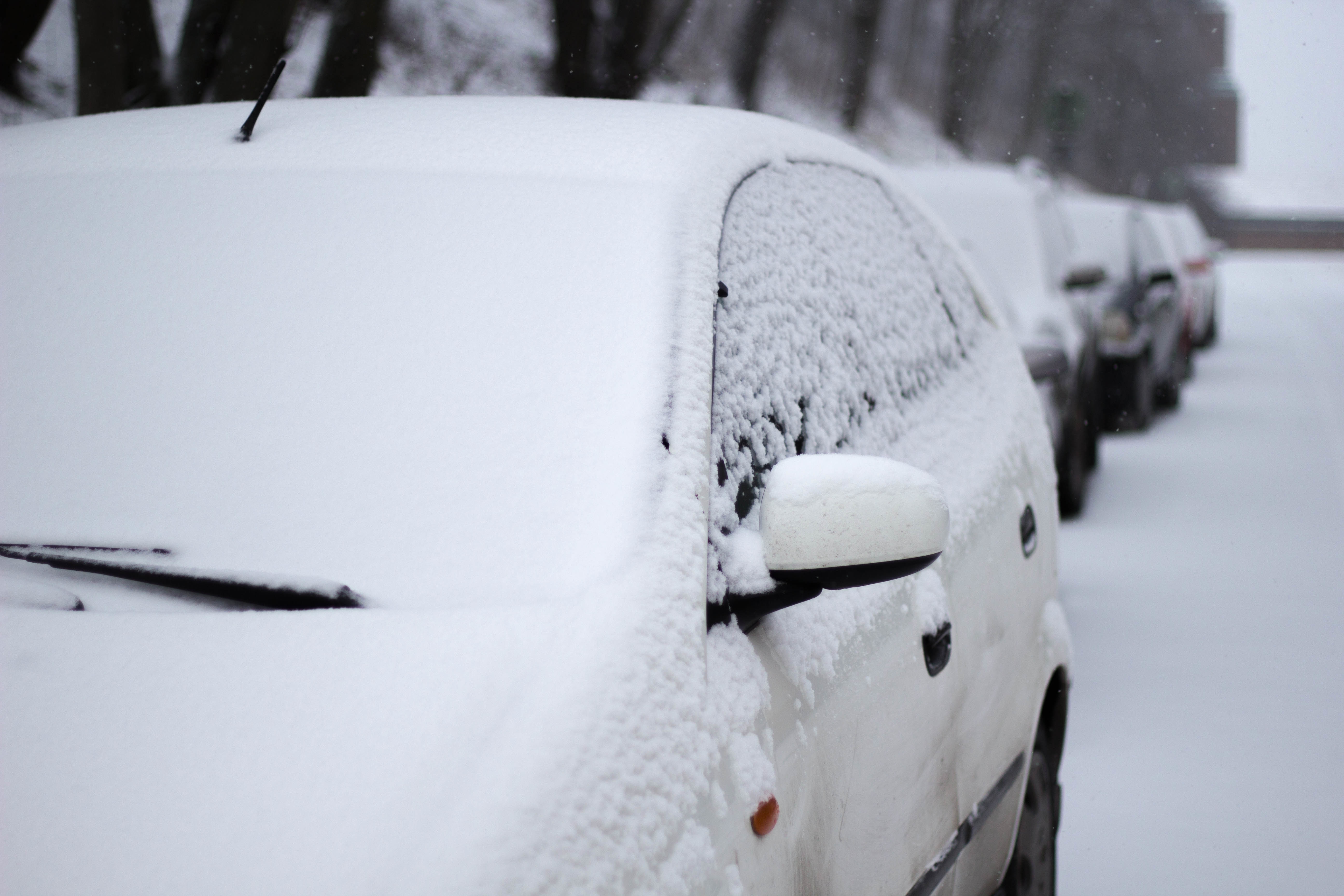 Nahaufnahme eines schneebedeckten Autos auf der Strasse im Winter.