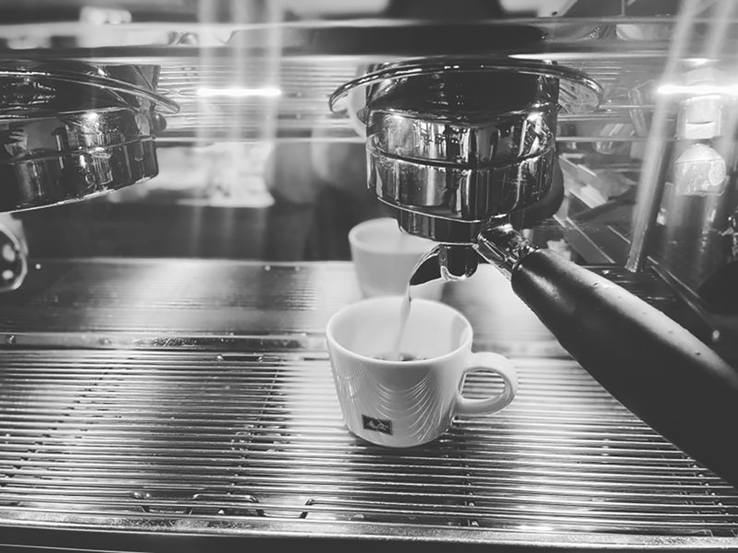 Eine Kaffeetasse steht unter einer Kaffeemaschine und wird gerade mit Kaffee befüllt.