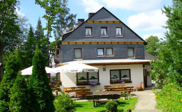 Außenansicht des Mollseifer Hofs mit Terrasse und Sonnenschirmen vor dem Haus.