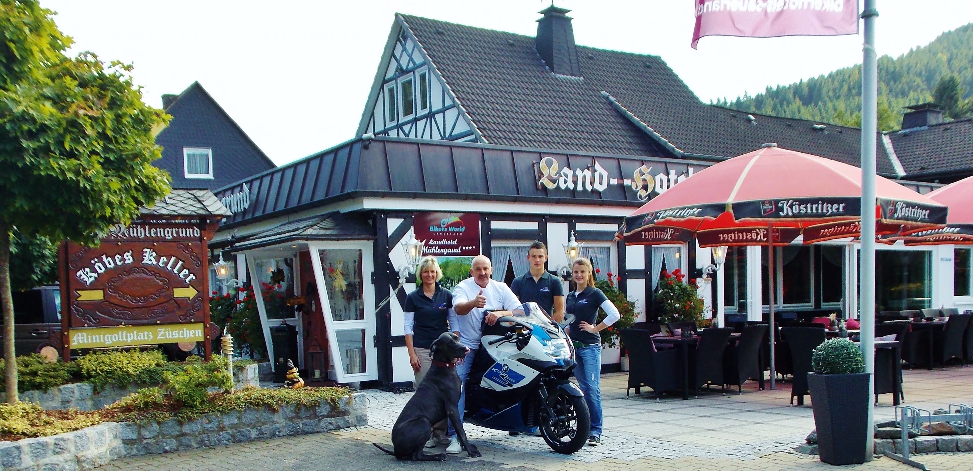 Vier Personen mit einem Motorrad stehen vor einem Restaurant. Vier Personen mit einem Motorrad stehen vor einem Restaurant.