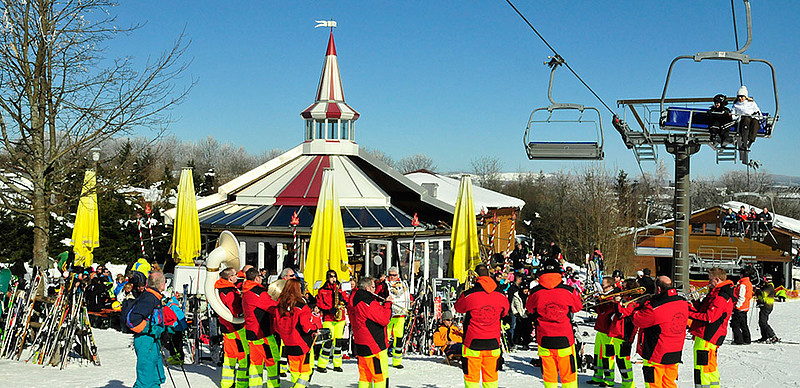 Eine Gruppe von Personen steht im Außenbereich einer Skihütte im Winter.