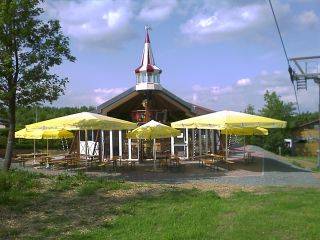 Eine bewirtschaftete Hütte deren Außenbereich mit Sonnenschirmen abgedeckt ist.