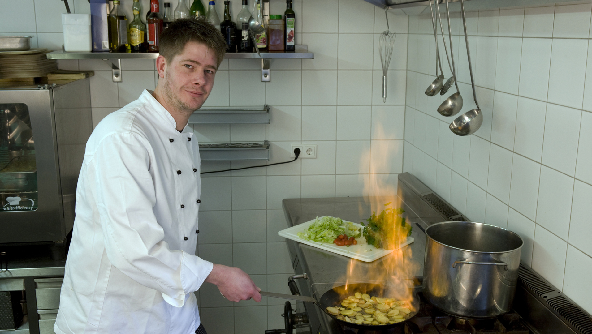 Ein Koch in seiner Küche beim zubereiten von Speisen.