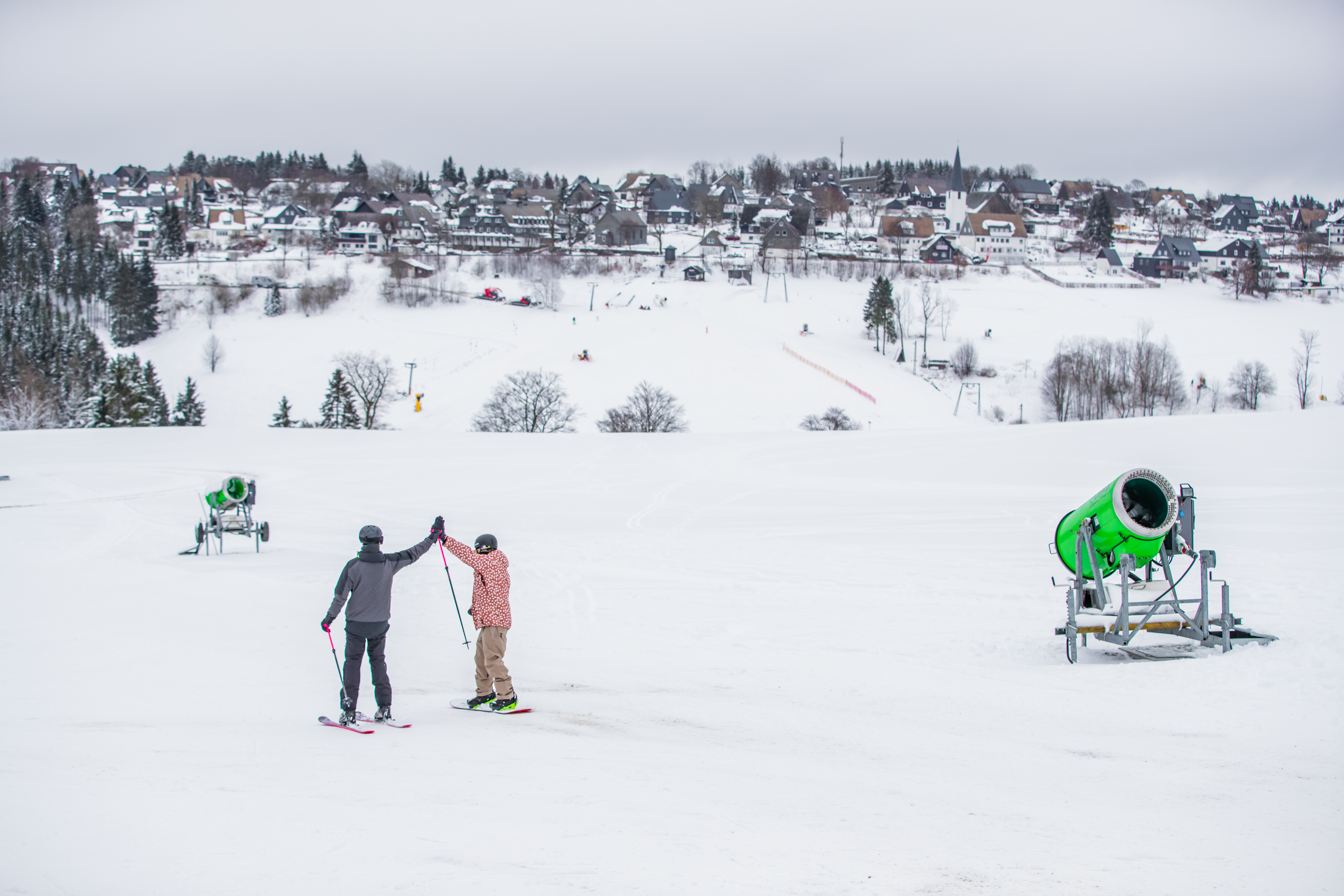 Zwei Skifahrer klatschen sich auf der Piste ab.