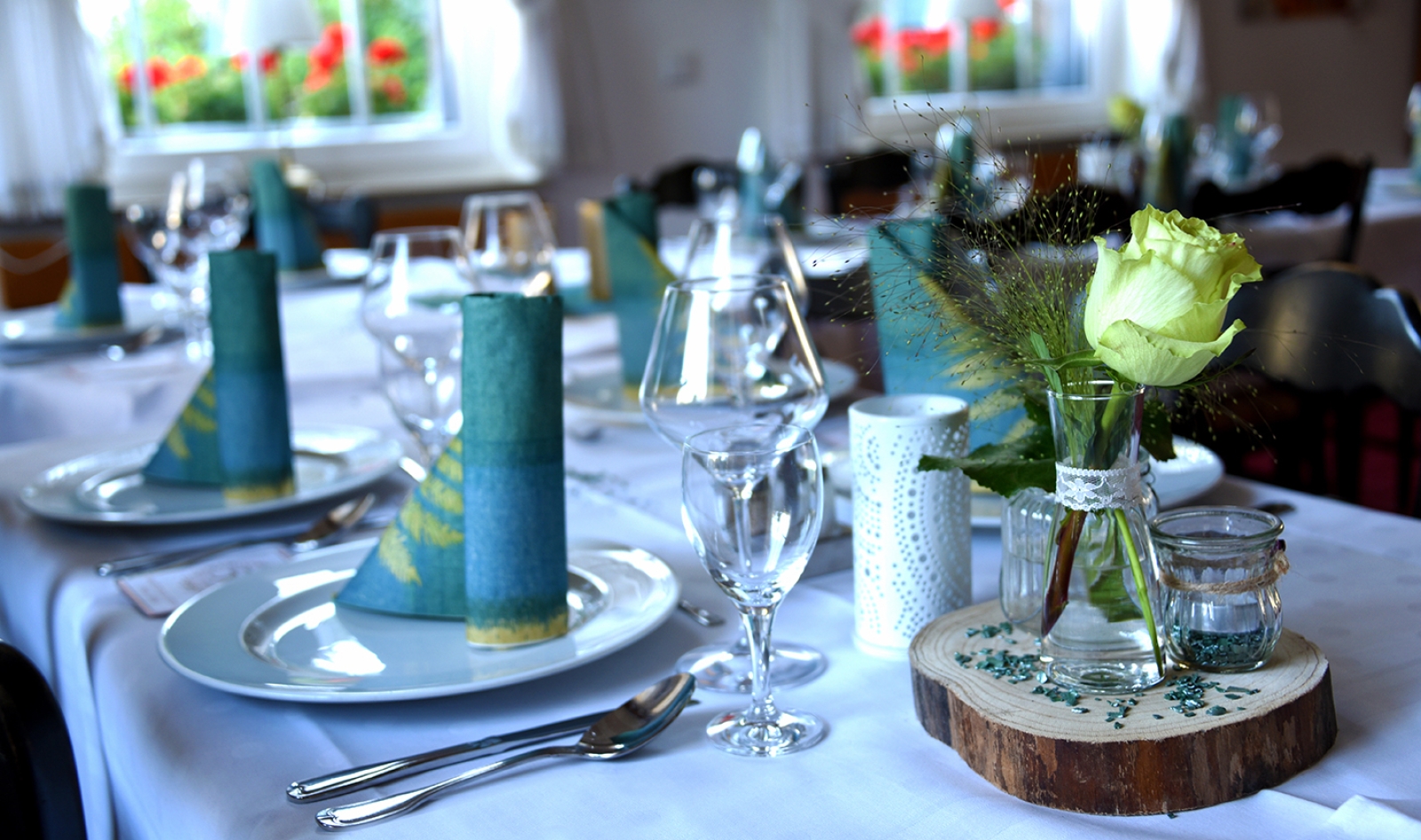 Ein mit Geschirr und Blumendekoration eingedeckter Tisch.