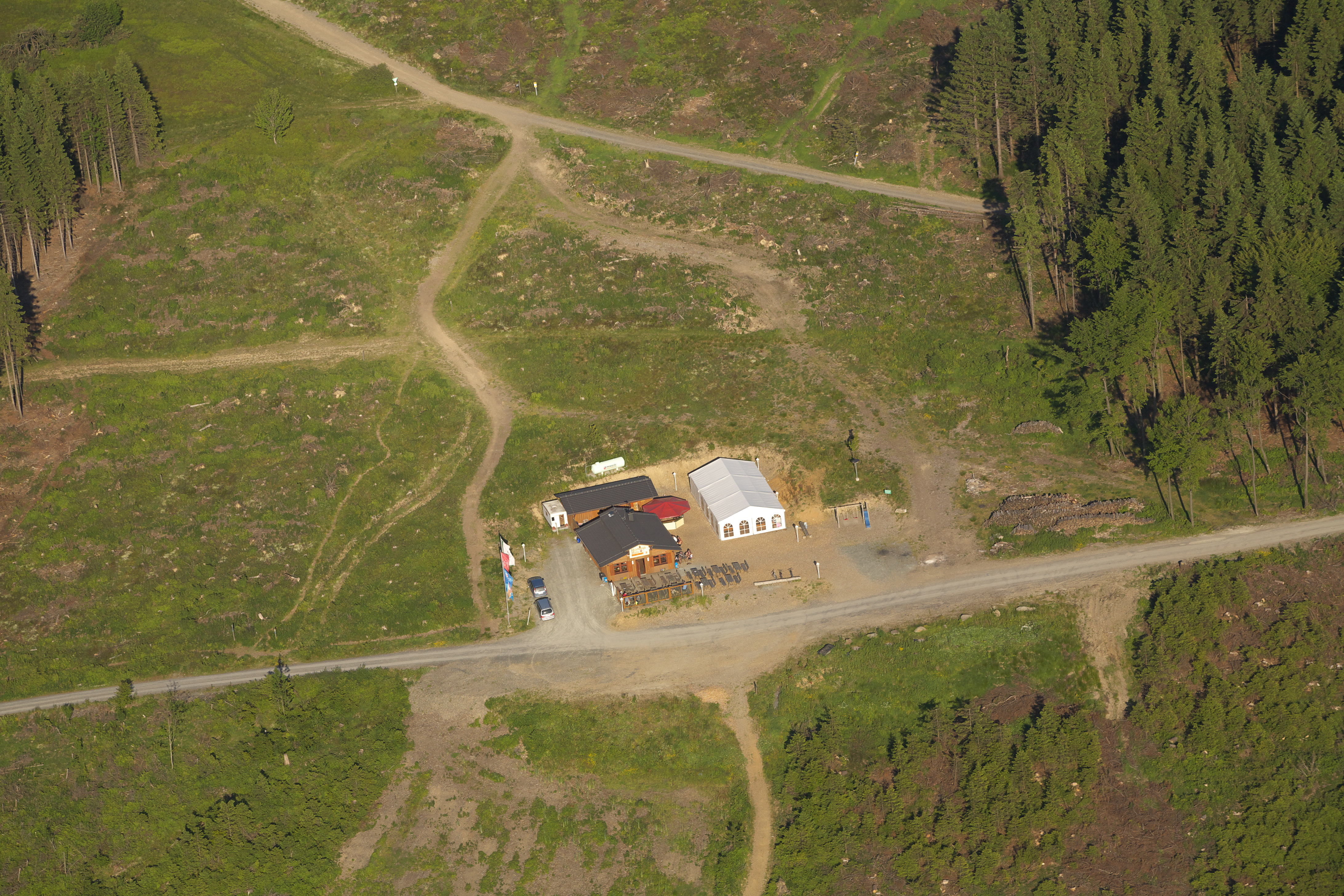 Drohnenaufnahme der Hochheide Hütte inmitten grüner Wiesen und einigen Wanderwegen.