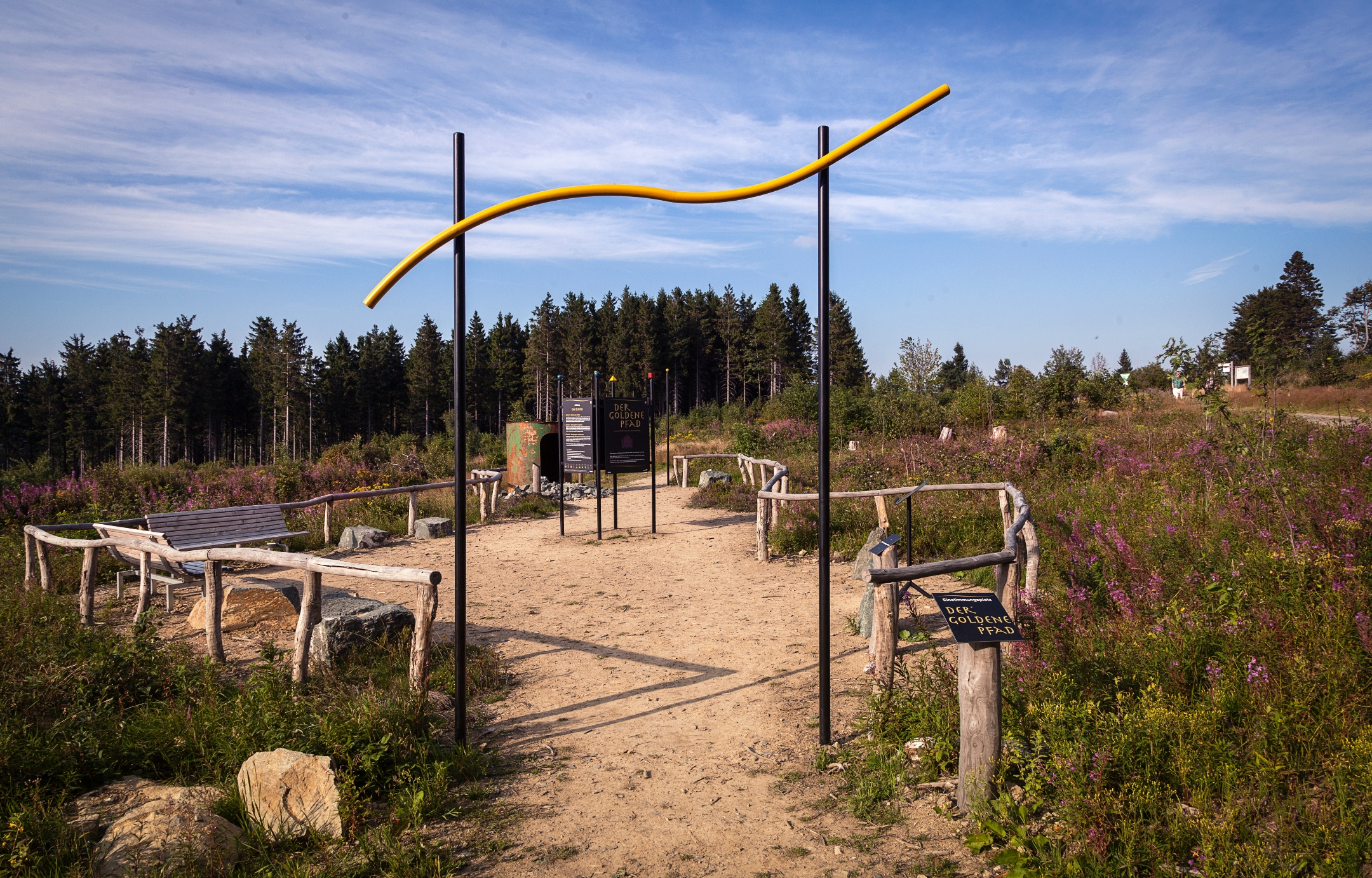 Ein großer Platz mit Bänken und Informationstafeln umgeben von Heidelandschaft.