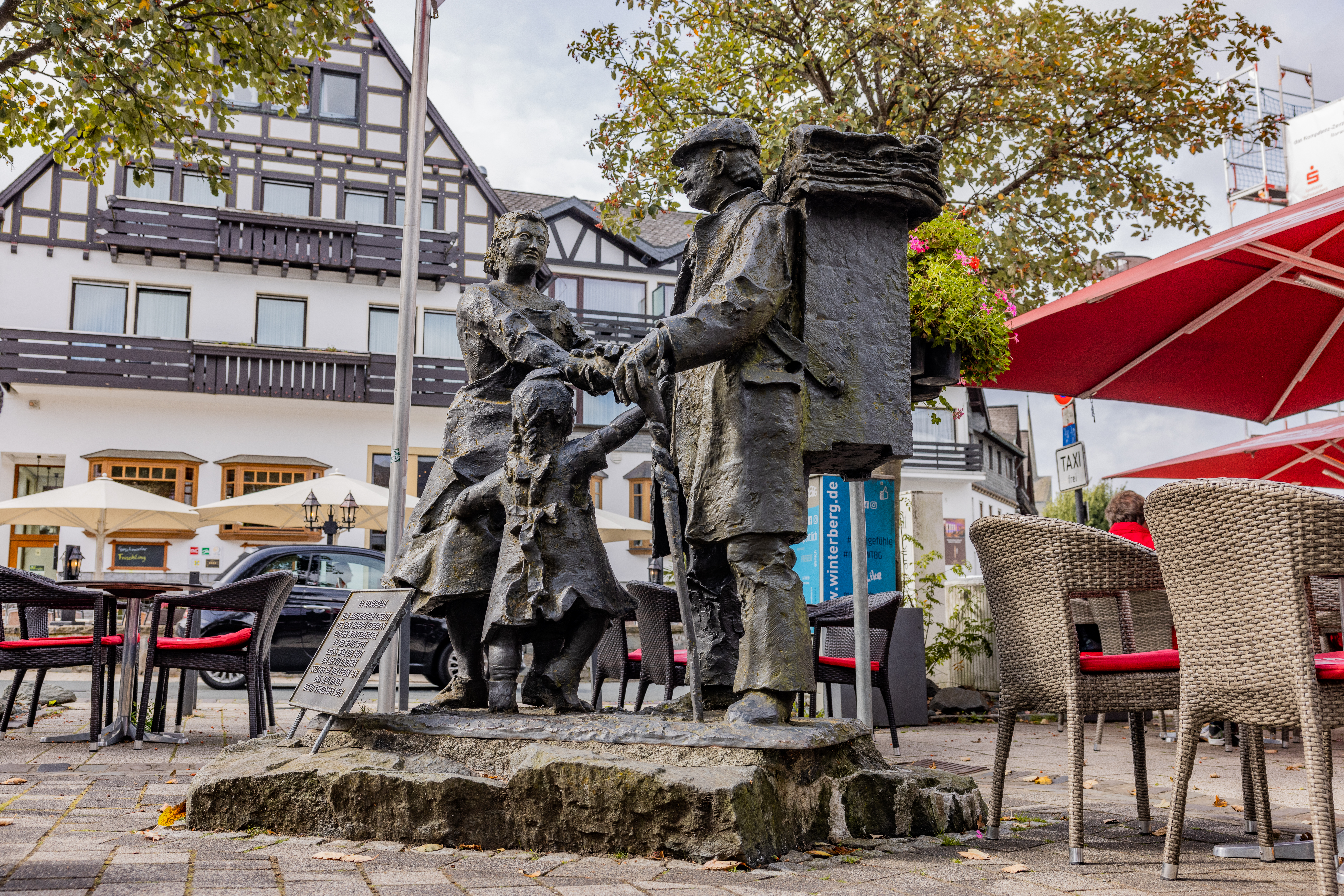 Ein eisernes Denkmal einer Frau, eines Kindes und eines Mannes mit einem Stock und großem Rucksack auf dem Rücken. Die drei Personen halten sich an den Händen.