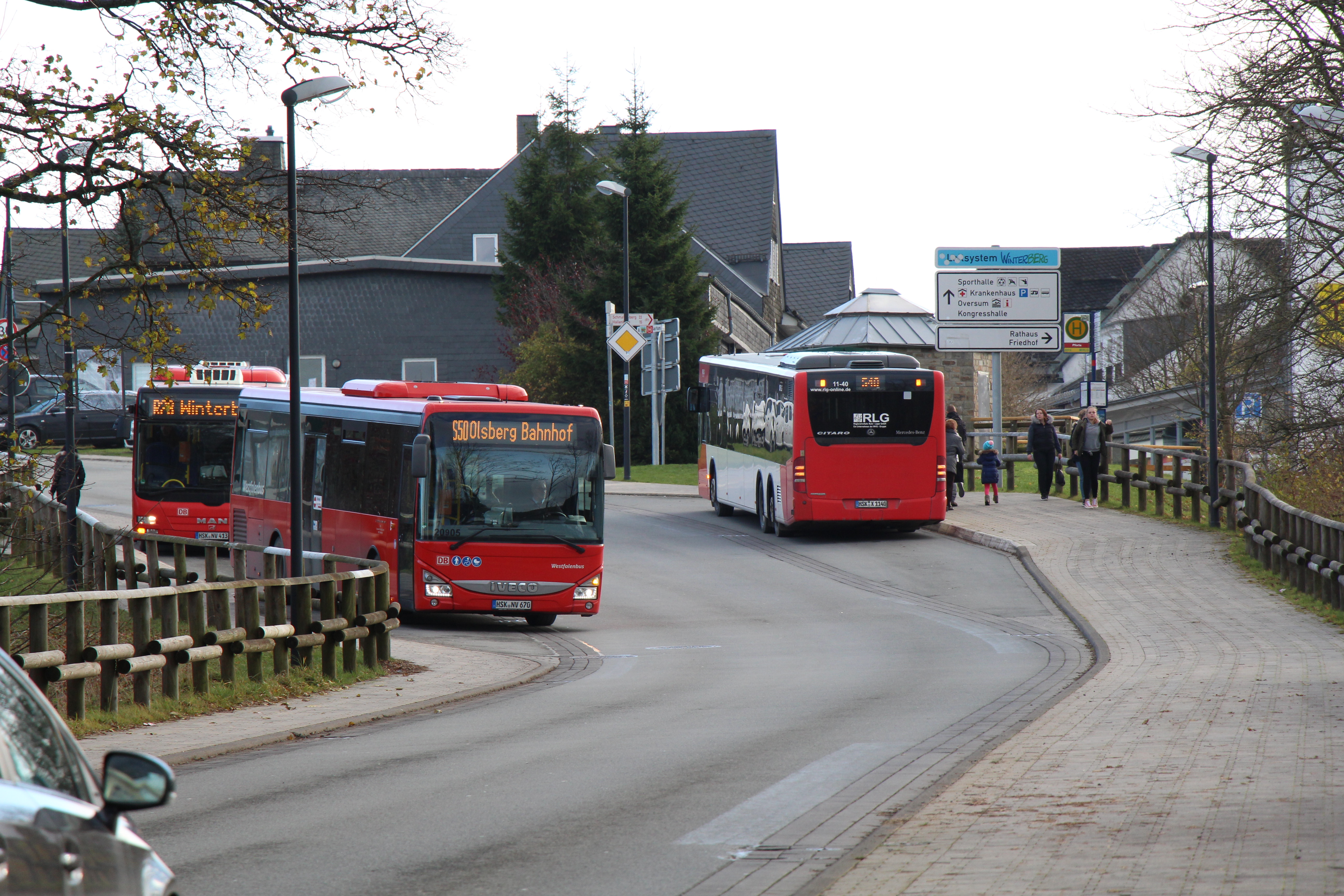 Zwei Busse halten an zwei gegenüberliegenden Bushaltestellen an der Straße.