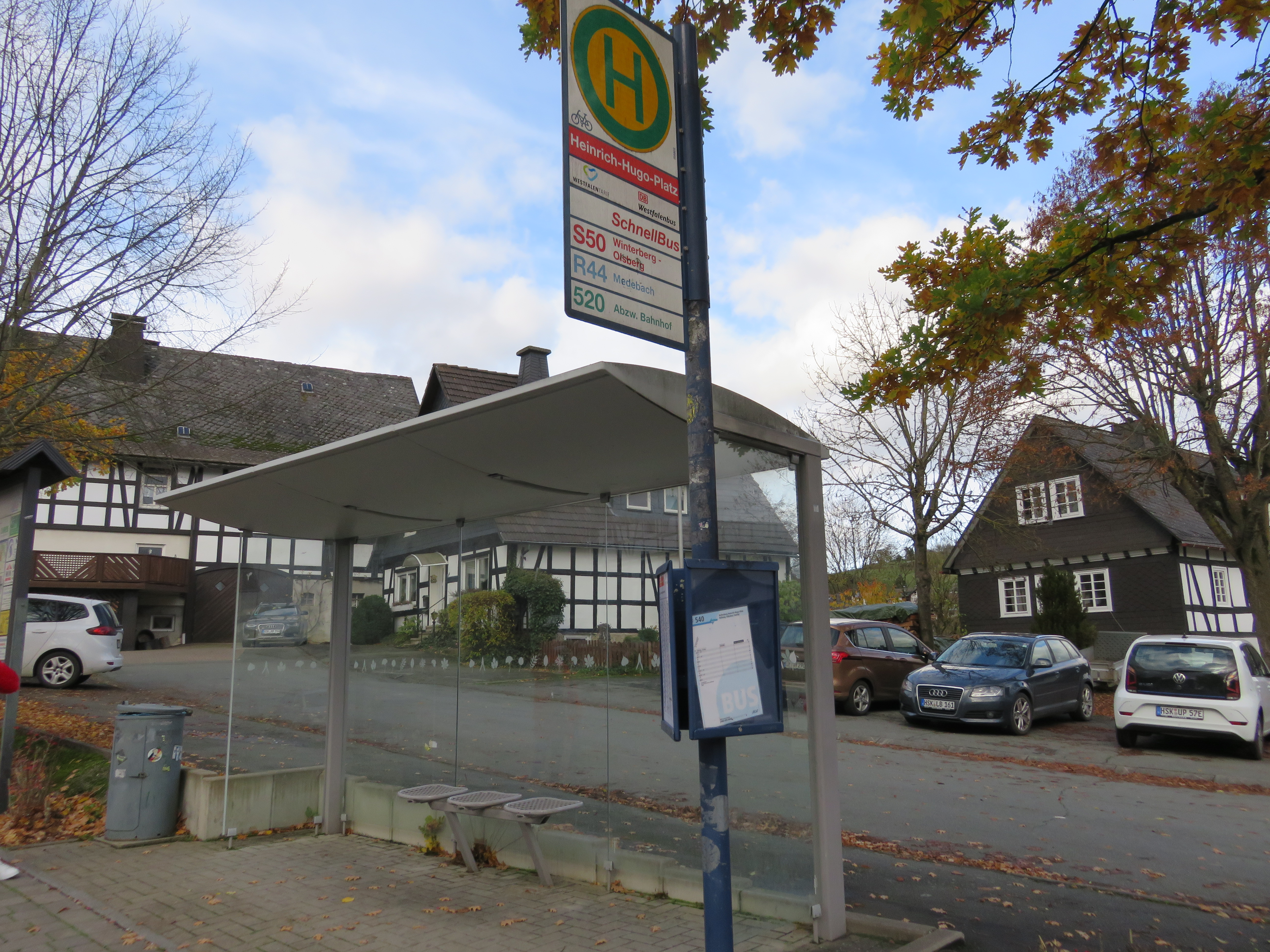 Ein Bushaltestellen-Häuschen mit einem Halteschild neben einer Straße.
