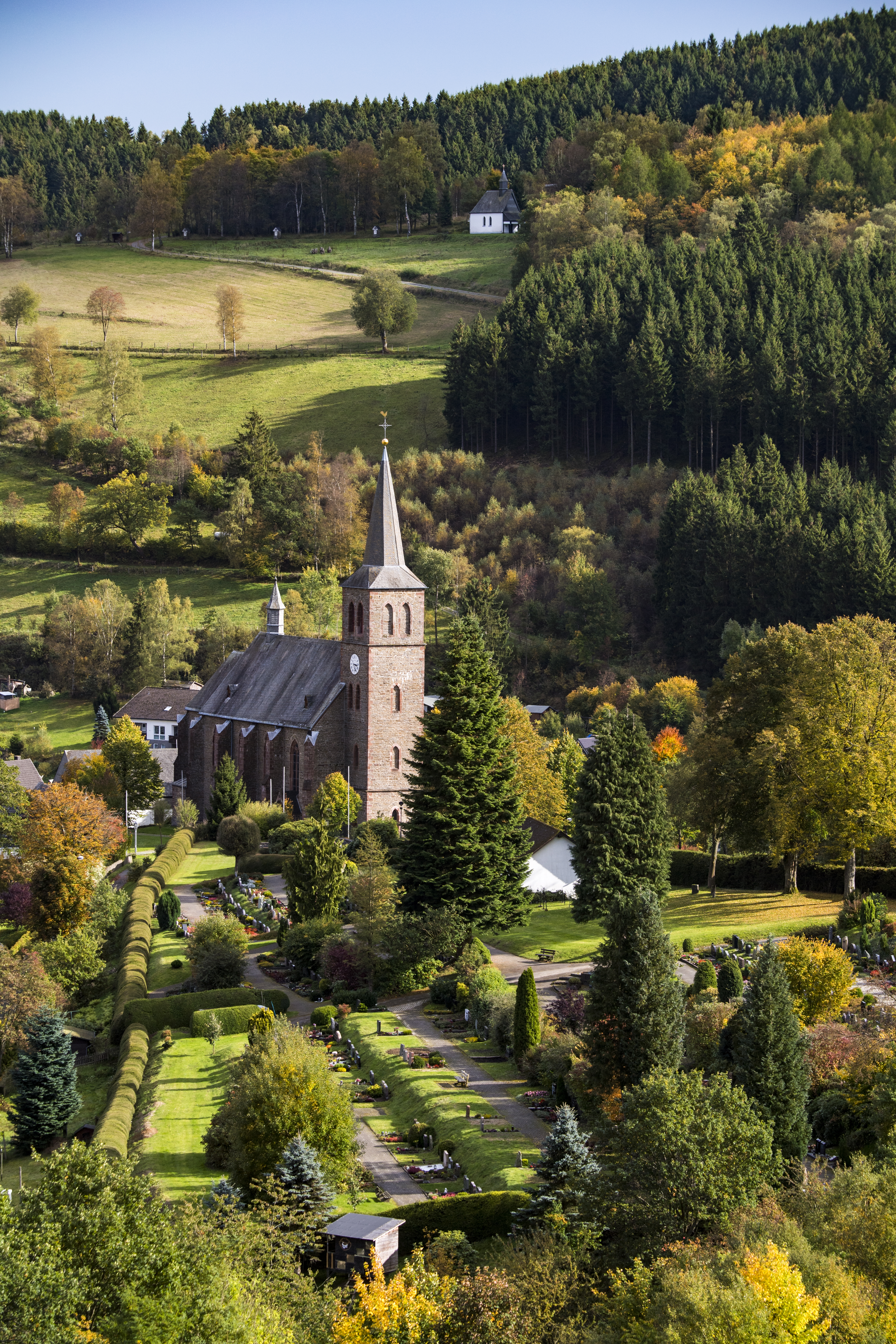 Drohnenaufnahmeeiner Kirche umgeben von Wiesen und Wäldern.
