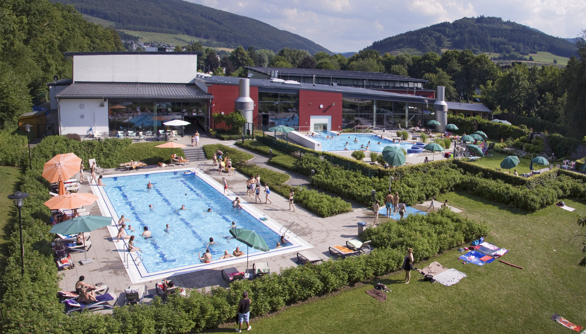 Der Außenbereich eines Schwimmbads mit zwei Außenbecken und Liegemöglichkeiten.